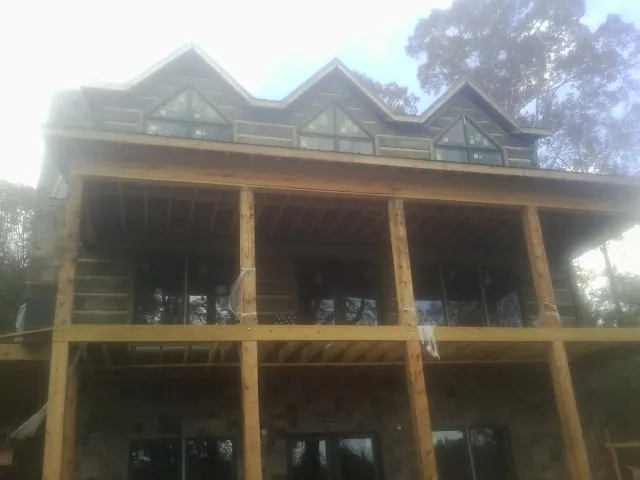 Dormers and porch framing on a large log home under construction — Roof Coating work by our crew in Mc Cool Junction