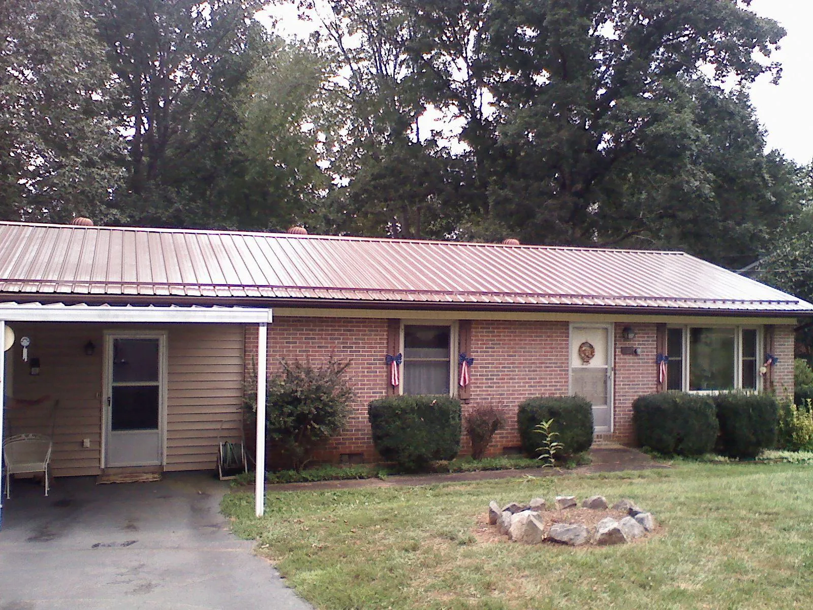 Bronze metal roof and carport on a brick ranch home — Roof Repair work by our crew in Mc Cool Junction